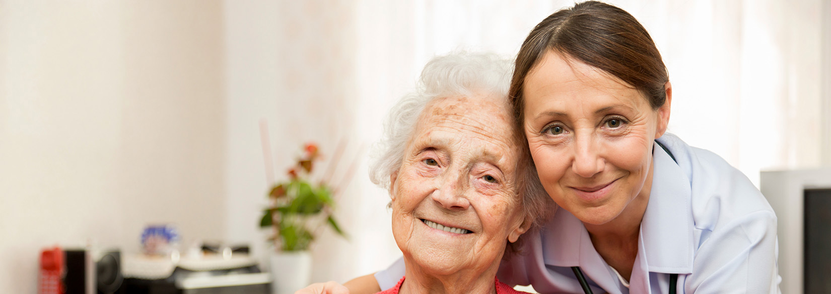 caregiver and elderly woman smiling at the camera